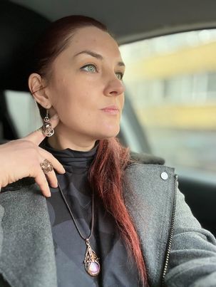 Wire wrapped pendants and earrings on red haired woman in grey jacket