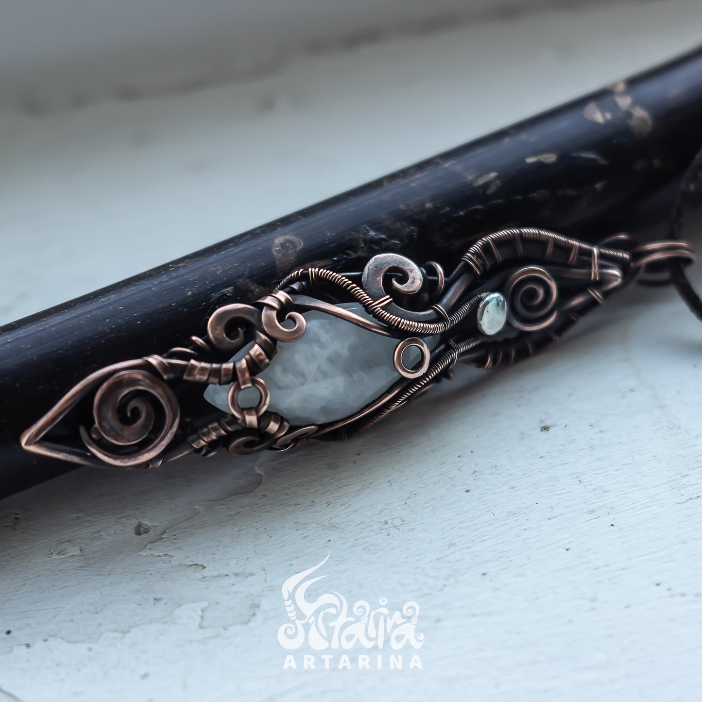 Decorative hair stick with intricate copper design on a light background
