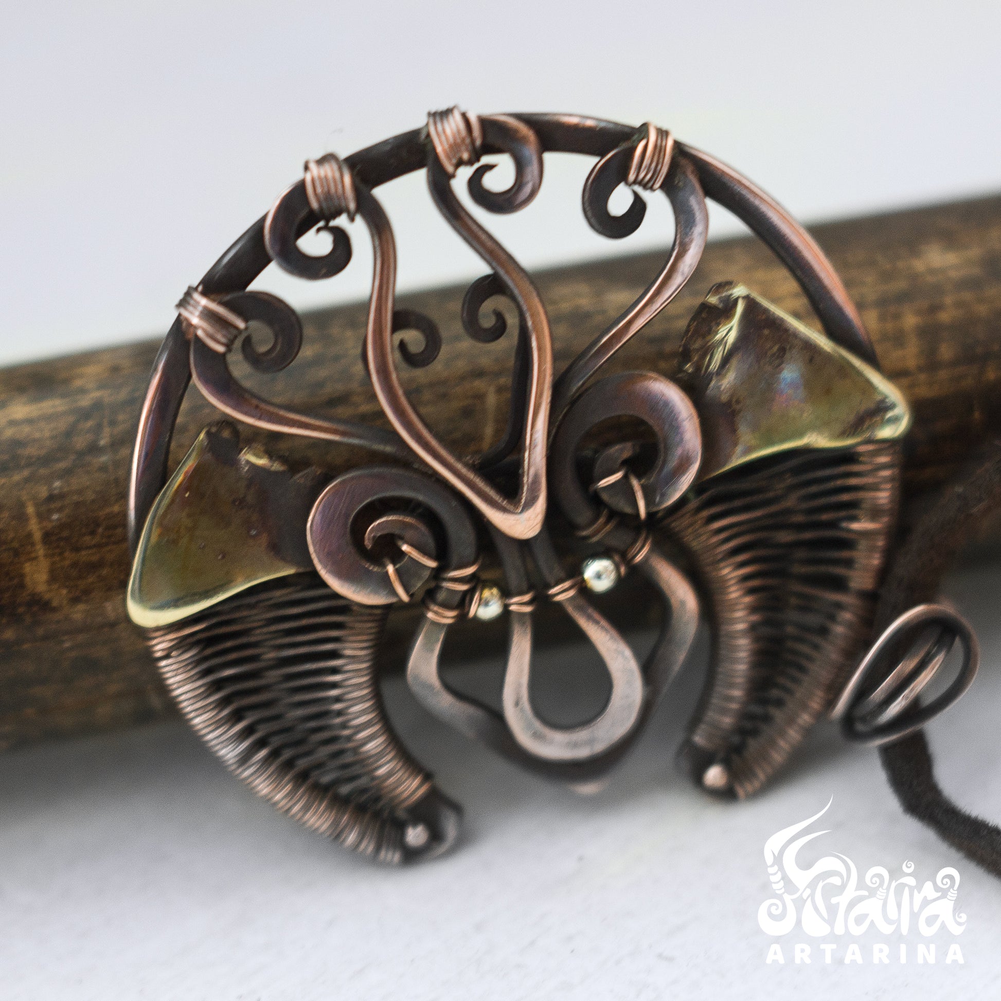 Copper butterfly pendant on a wooden stick with a white background