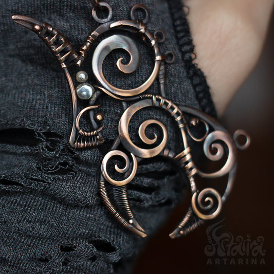 Ornate metal pendant with intricate designs on a dark fabric background