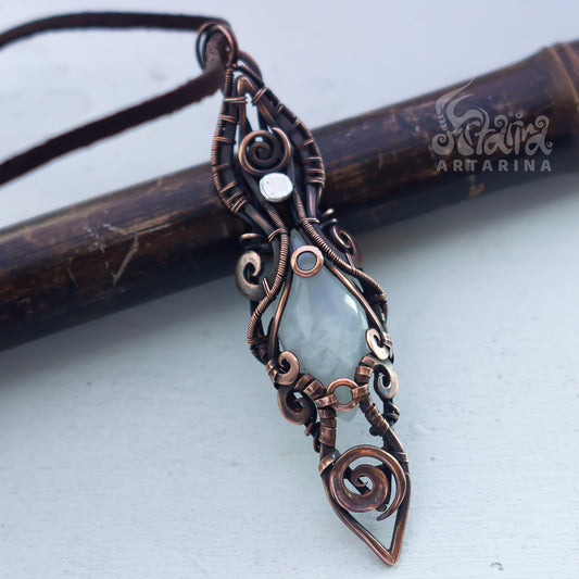Copper wire-wrapped pendant with a central stone on a light background