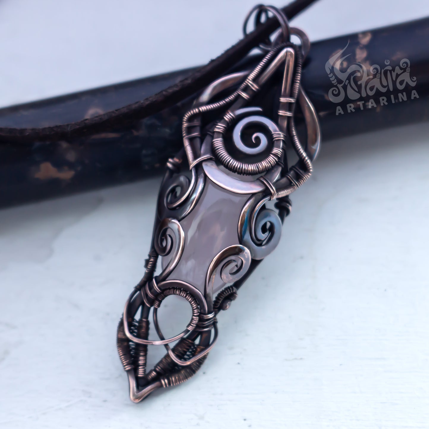 Ornate copper pendant with intricate designs on a light background