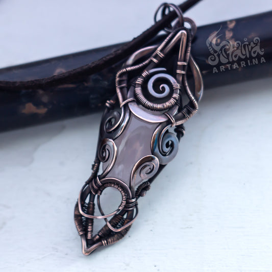 Ornate copper pendant with intricate designs on a light background