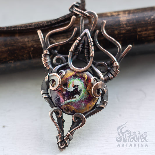 Ornate copper and silver pendant with a colorful central stone on a white background