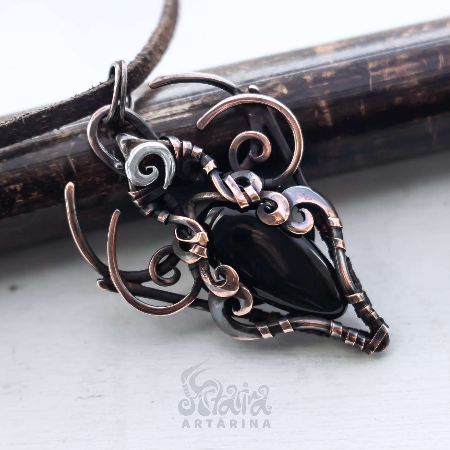 Ornate copper and silver pendant on a white background with 'Artarina' branding.