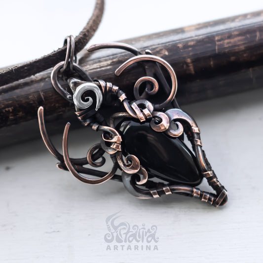 Ornate copper and silver pendant on a white background with 'Artarina' branding.