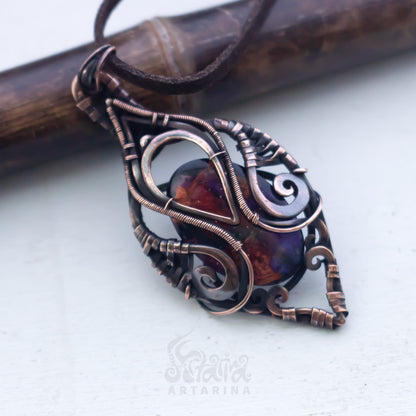 Copper wire-wrapped pendant with a central gemstone on a white background