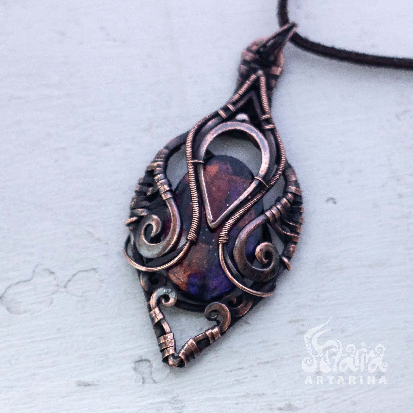 Ornate copper pendant with a dark stone on a light gray background