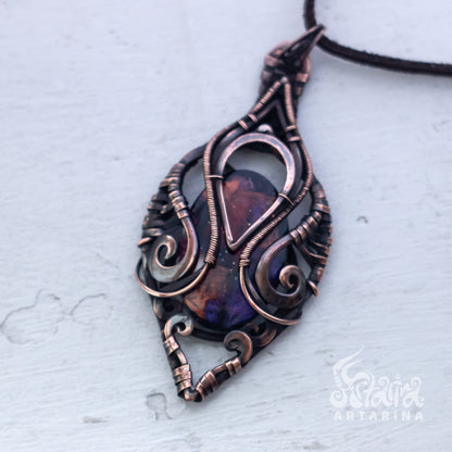 Ornate copper pendant with a dark stone on a light gray background